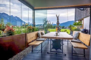 Ein Wintergartenanbau in Abendstimmung in Anthrazit mit geschlossenem, indirekt mit LED beleuchtetem Lamellendach und teilweise geschlossenen Glasschiebetüren von Moltke.