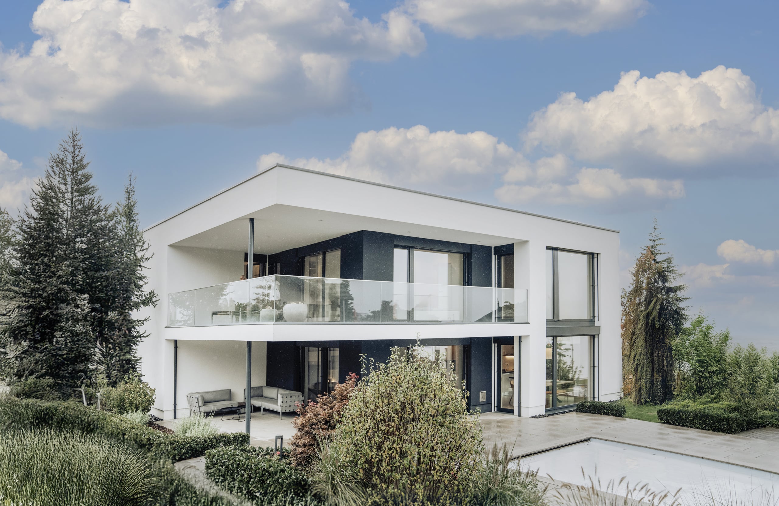 Einfamilienhaus mit Flachdach, bodentiefer Verglasung, überdachter Terrasse, Balkon und Nurglasgeländer im Musterhauspark Eugendorf.