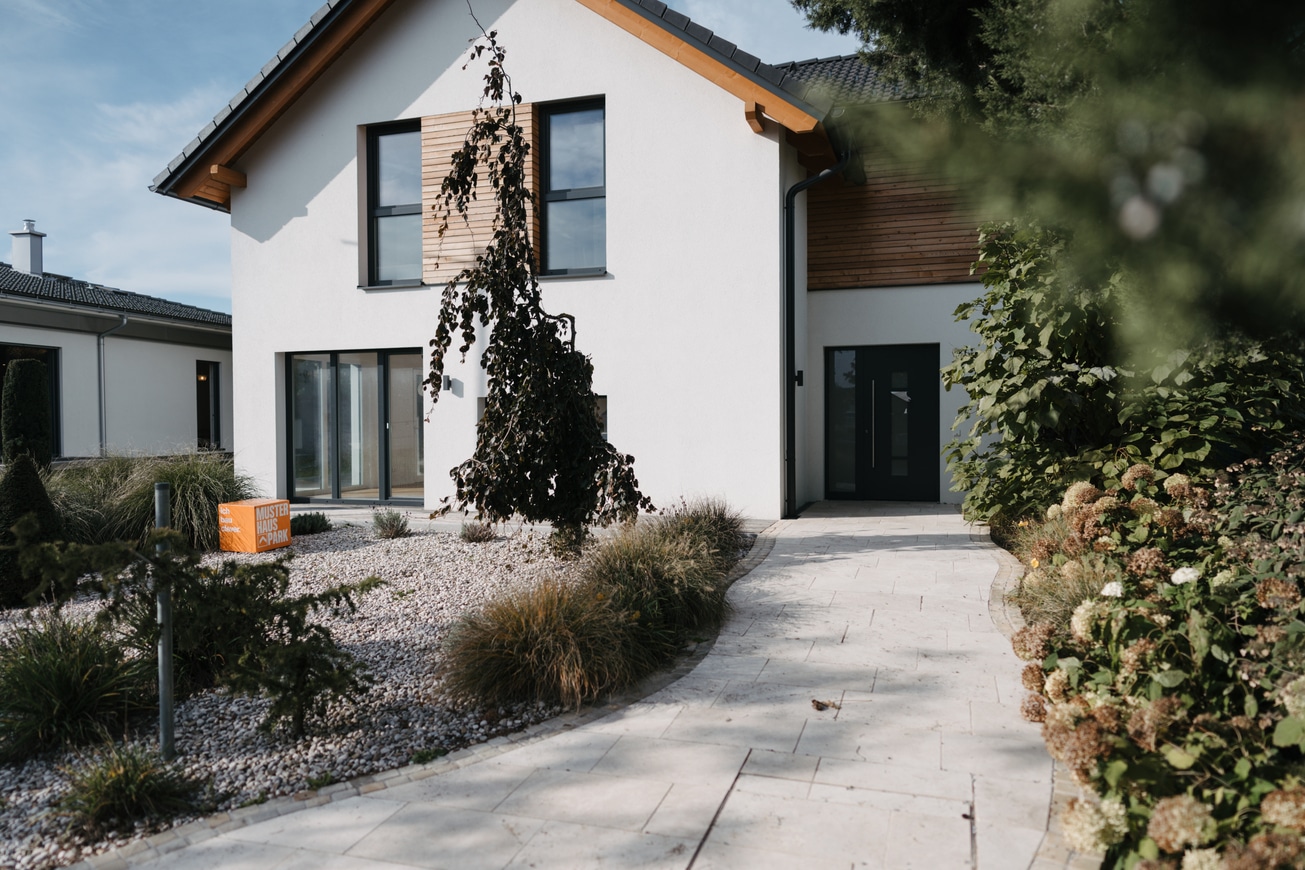 Einfamilienhaus mit Fassadenelementen aus Holz, Terrassenschiebetüren und Fenster mit Alurahmen in Anthrazit und einem barrierefreien Hauseingang im Musterhauspark Haid.