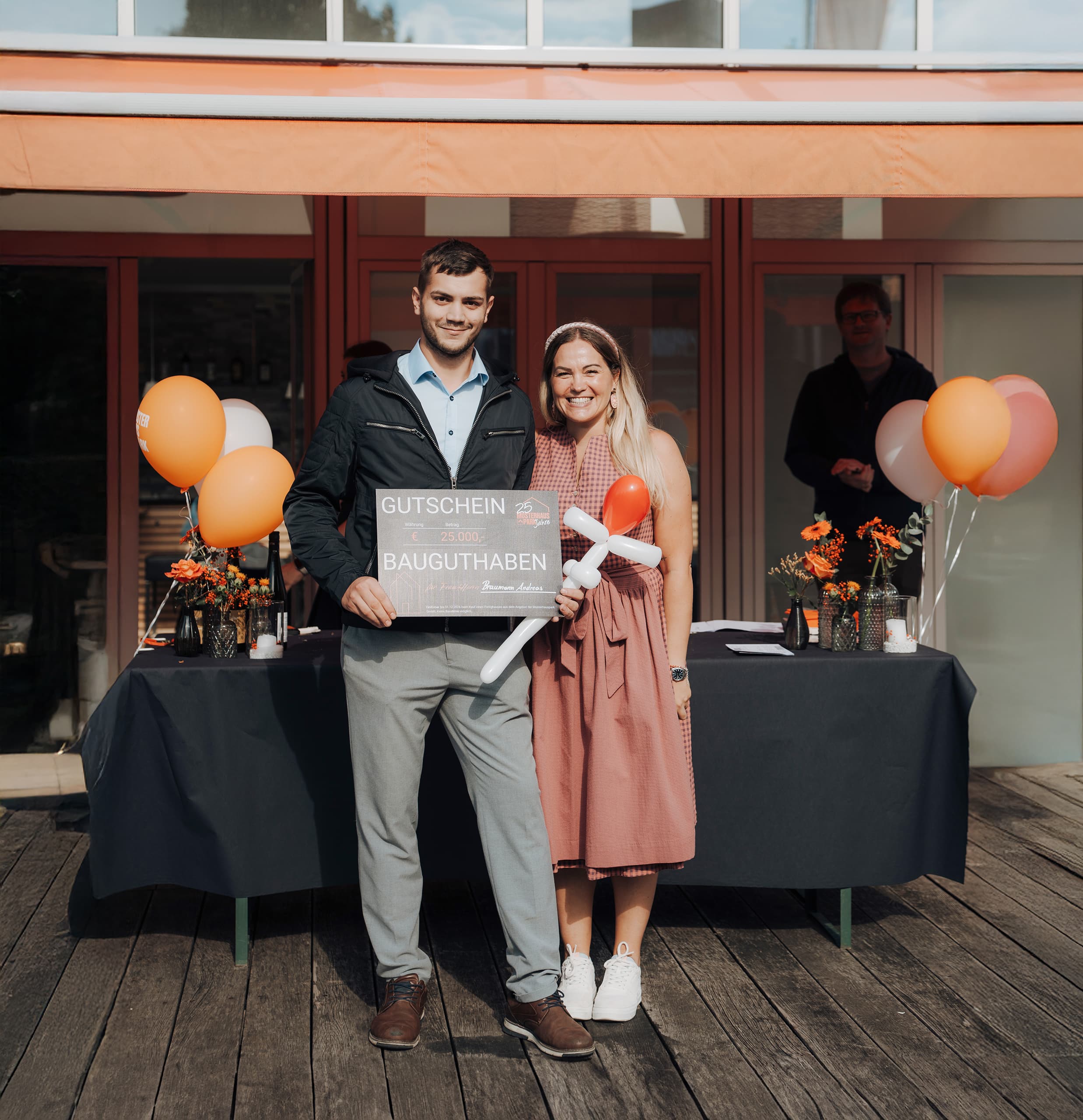 Der Gewinner des € 25.000,- Bauguthabens - mit Musterhauspark-Geschäftsführerin Julia Mauberger MBA, akad. MM - auf der Feier des 25-jährigen Bestehens des Musterhausparks, im Musterhauspark Eugendorf.