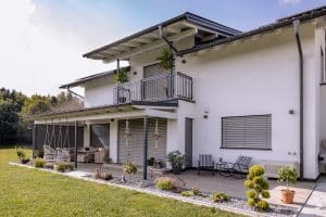 Newo Sonnen- und Insektenschutz zeigt ein Einfamilienhaus dessen Fenster und Terrassentüren mit Raffstore und Textilscreen beschattet werden.
