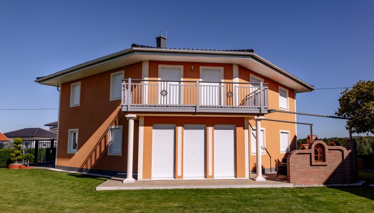 Newo Sonnen- und Insektenschutz zeigt ein Einfamilienhaus dessen Fenster und Terrassentüren mit Rolladen beschattet werden.