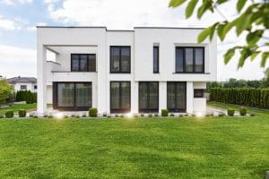 Newo Sonnen- und Insektenschutz zeigt eine moderne Flachdach-Villa dessen Fenster und Terrassentüren mit Raffstore beschattet werden.