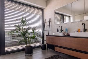 Newo Sonnen- und Insektenschutz zeigt ein Badezimmer, mit Blick durch ein Fenster mit Raffstores.