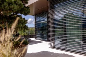 Wohnung mit moderner Eckverglasung mit schwarzem Alu-Rahmen und halboffenen silbernen Raffstores von Newo.