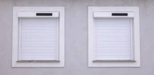 Zwei Fenster mit weisser Außenjalousie mit Vorbaurolladen und Solarantrieb von NEWO für modernen Sonnen-, Sicht- und Wärmeschutz.