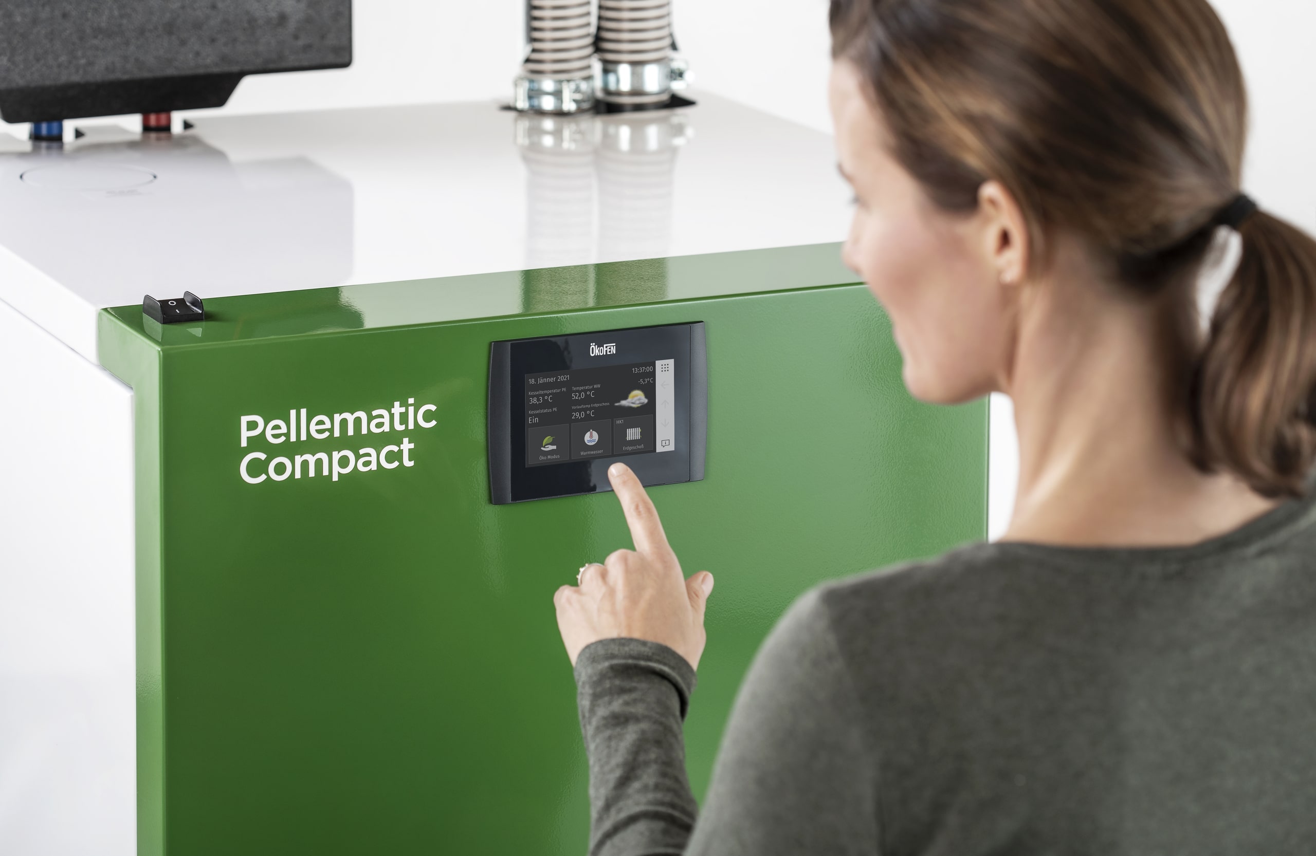Eine Frau bei der Bedienung des Touchpanels einer Pellematic Compact von ÖkoFEN.