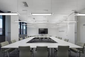 Opple Lighting zeigt einen großen hellen Besprechungsraum mit an der Decke aufgehängten rechteckigen Leuchten.