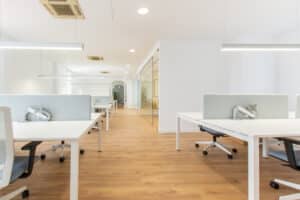 Opple Lighting zeigt ein helles Großraumbüro mit an der Decke aufgehängten rechteckigen Leuchten und integrierten Spotleuchten.