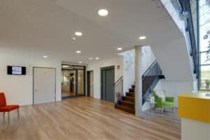 Opple Lighting zeigt einen großen Empgangsraum mit Akustikdecke und integrierten großen Einbauspots.