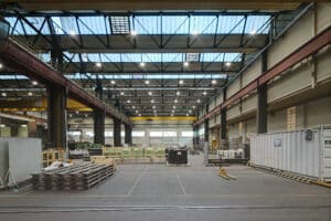 Opple Lighting zeigt eine große Lagerhalle mit vielen ringförmigen, an Metallschienen befestigten Spotlampen.