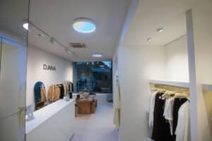 Opple Lighting zeigt den Verkaufsraum eines Modegschäftes mit großen runden Aufbauleuchten mit verschiedenen Lichtfarben, Spotlampen auf einer Schiene und kleine Einbauspots.