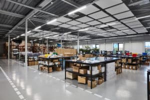 Opple Lighting zeigt eine große Versandhalle mit vielen stabförmigen, auf einer Schiene montierten Leuchten.