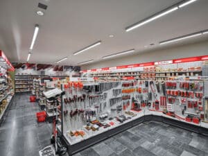 Opple Lighting zeigt einen Verkaufsraum für Werkzeug mit vielen stabförmigen, auf der Decke montierten Leuchten und dazwischen Einbauspots.