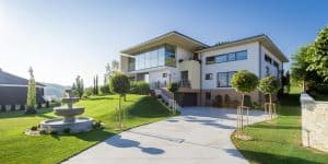 Villa mit Flachdach, Garage, überdachter Terrasse und einer großzügigen Auffahrt und Vorgarten mit Brunnen aus der Vogelperspektive von Planungsbüro Schaufler.