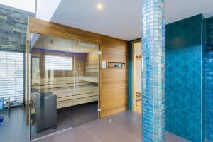 Privater Wellnessbereich mit Saunakabine mit Holzvertäfelung, Säulen mit blauen Mosaikfliesen und blauen Wandfliesen mit Ornamenten von Planungsbüro Schaufler.