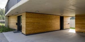 Hauseingang und Carport eines Einfamilienhauses mit Bau- und Fassadenelementen aus Beton und Holz mit Spots in der Betondecke von Planungsbüro Schaufler.