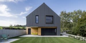 Einfamilienhaus mit Satteldach, Terrasse mit integrierter Überdachung, Blechverkleidung, Bau- und Fassadenelementen aus Beton und Holz und einem großen Garten von Planungsbüro Schaufler.
