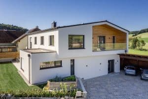 Einfamilienhaus in verschachtelter Bauweise mit Satteldach und einem Balkon mit Nurglasgeländer und holzverkleideten Wänden von Planungsbüro Schaufler.