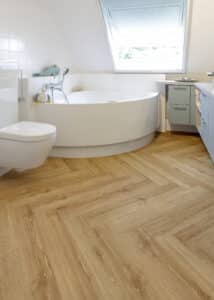 Ein modernes Badezimmer mit freistehender Badewanne und elegantem Fischgrätboden in natürlicher Holzoptik – von Project Floors.