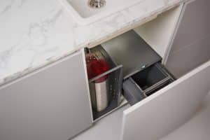 Ein PRO3 CUBE von Quooker der sich elegant neben dem ausziehbaren, doppelten Abfallbehälter unter der Spüle verstauen lässt.