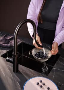 Eine "Quooker Flex Round"-Küchenarmatur in Gunmetal auf schwarzer Marmorarbeitsplatte mit flexibel ausziehbarer Schlauchbrause ideal zum Waschen von Früchten und Alltagsgebrauch in der Küche von Quooker.