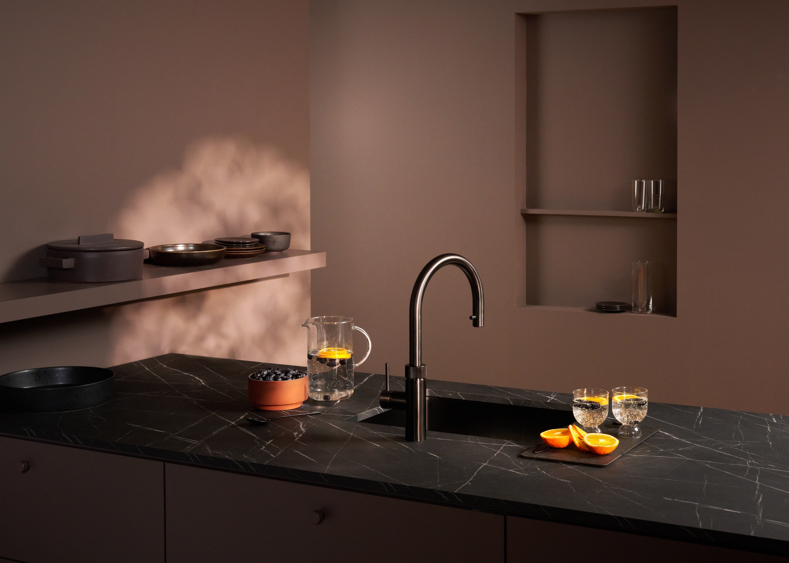 Ein “Quooker Flex Round”-Wasserhahn in Gunmetal auf einer schwarzen Marmor‑Küchenarbeitsplatte von Quooker.