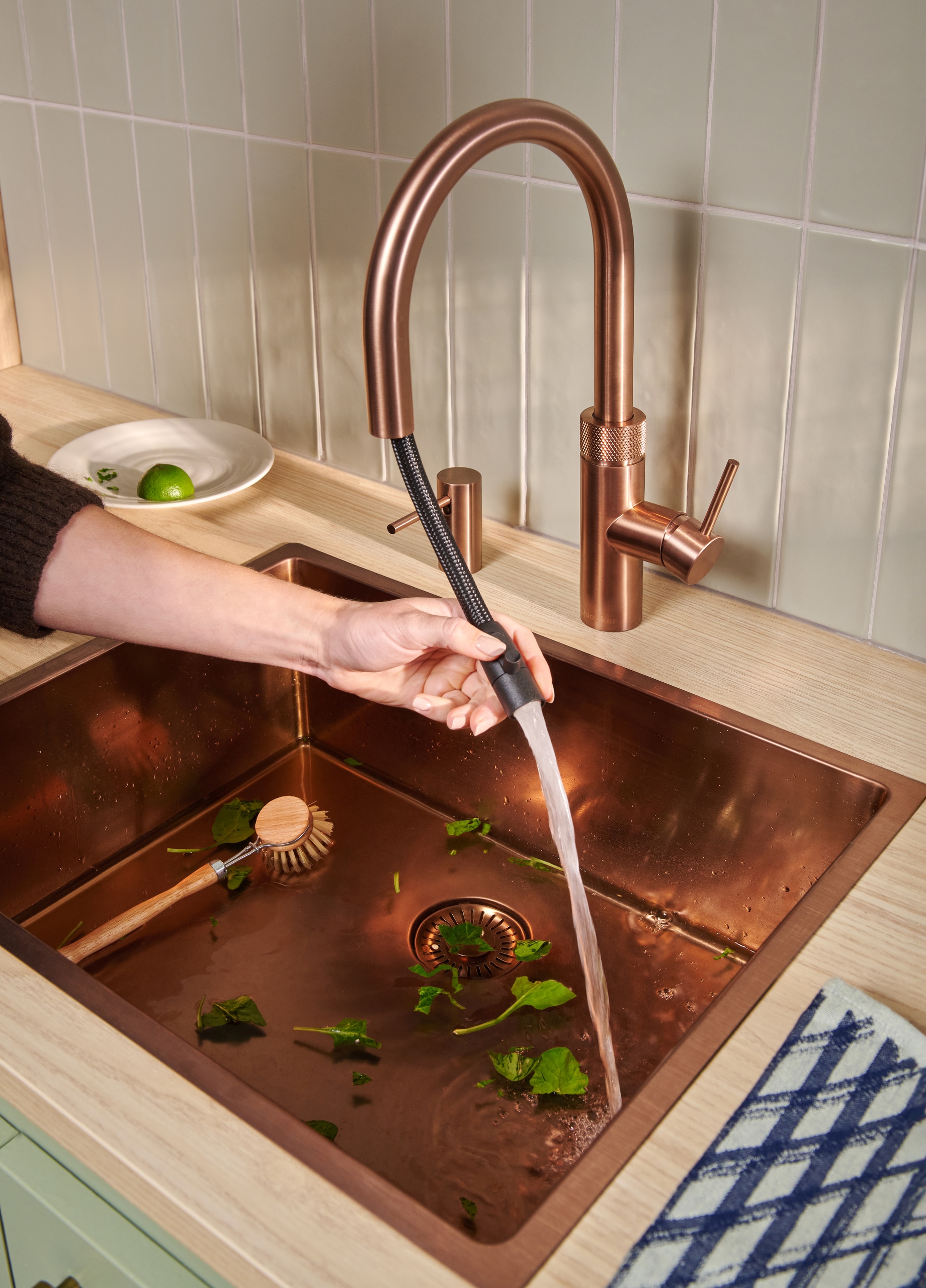 Ein “Quooker Flex Round”-Wasserhahn mit passendem eingebauten Seifenspender in Rosé‑Kupfer mit ausziehbarem Auslauf für eine effektive Spülenreinigung und flexible Nutzung von Quooker.