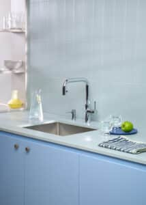 Eine “Quooker Flex Square”-Armatur in glänzendem Chrome mit passendem Seifenspender in einer hellblauen Küche mit modernem Design von Quooker.