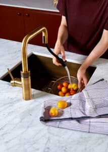 Ein “Quooker Flex Square”-Wasserhahn in Patina‑Messing mit einem flexiblen schwarzen Schlauch‑Auszug und modernem, kantigem Design von Quooker.