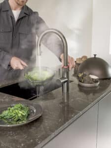 Die Armatur Flex Round in Gunmetal mit kochender Wasserausgabe auf einer edlen Marmor-Arbeitsplatte von Quooker.
