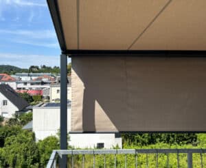Beige Senkrechtmarkise auf Dachterrasse mit anthrazitfarbener Konstruktion und über einem Metallgeländer von Sonnenschutz Rachbauer.