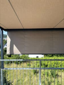Beige Senkrechtmarkise auf Dachterrasse mit anthrazitfarbener Konstruktion und über einem Metallgeländer von Sonnenschutz Rachbauer.