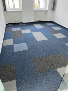 Ein Büro mit frisch verlegtem Teppichboden in verschiedenen blauen Quadraten, gleichmäßig und modern ausgeführt von Raumgestaltung Gruber.