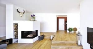 Offener Wohnraum mit Kamin und Holzlager, Holdielen und Treppen zum Couchbereich von Regnauer Fertighaus.