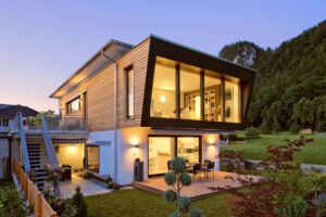 Eine moderne Villa bei Nacht mit seitlichem Außenaufgang und großflächigen Fensterflächen, dezent beleuchtet von Regnauer.