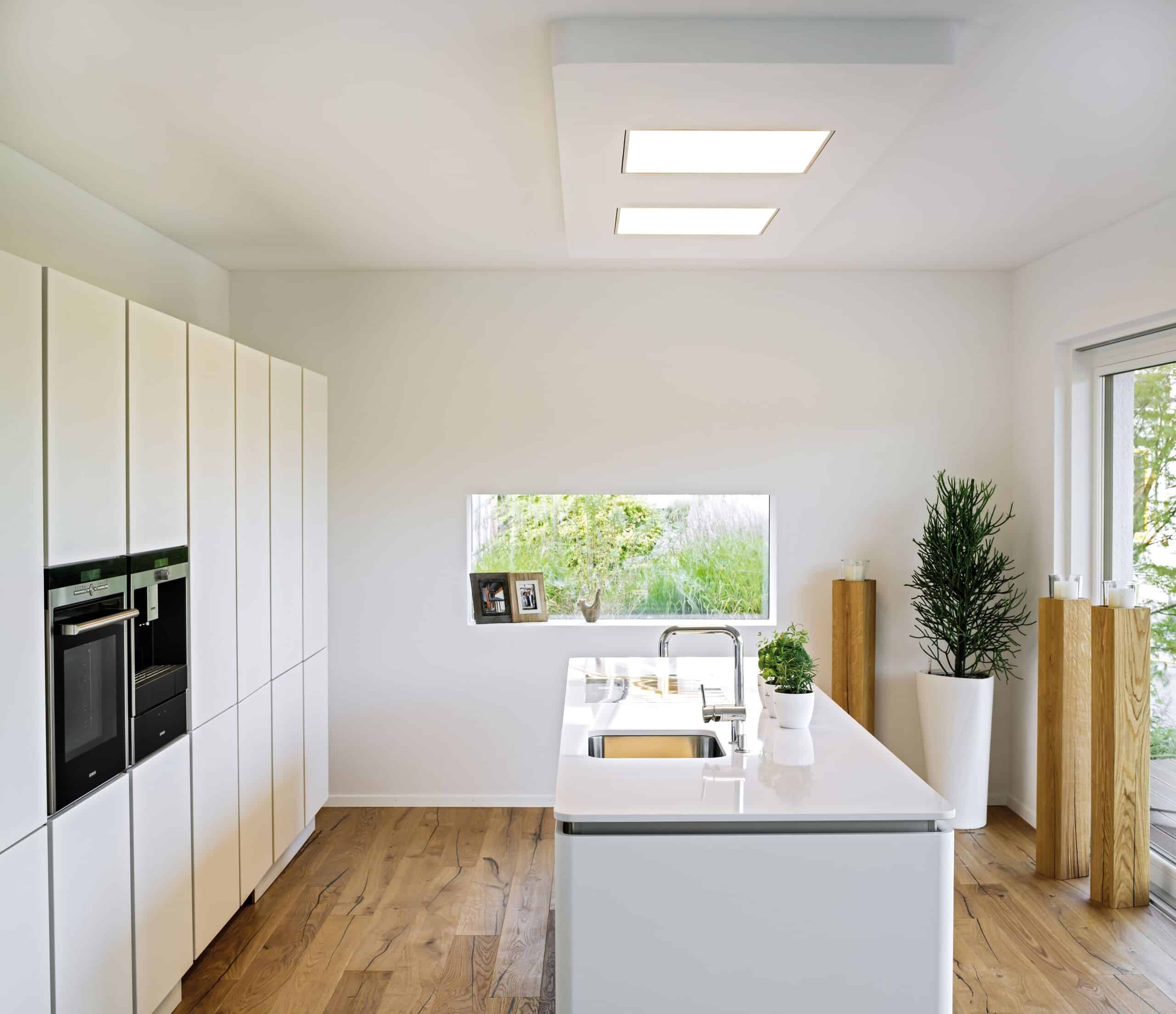 Eine moderne offene Küche mit Kochinsel, bodentiefer Terrassenschiebetür und seitlicher Festverglasung von Regnauer.