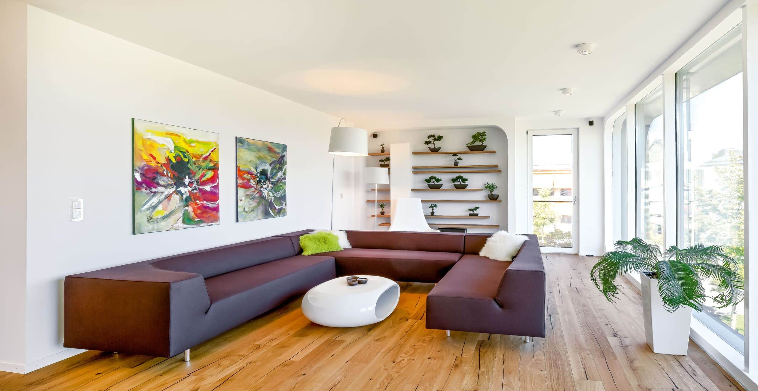 Offenes Obergeschoss mit U-förmiger Couch, großflächiger bodentiefer Festverglasung und Glasfront mit Balkontür von Regnauer.