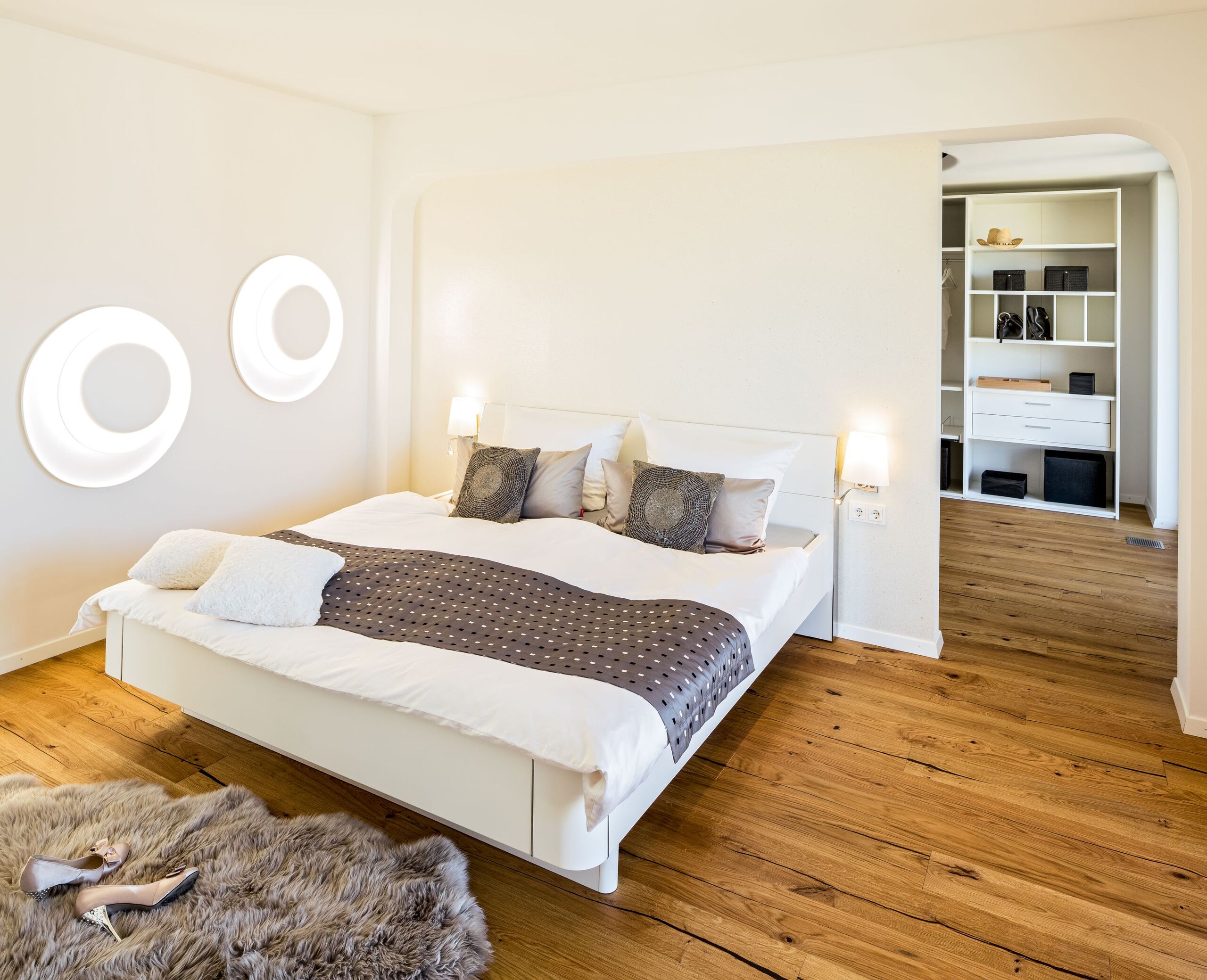 Ein Schlafzimmer mit Durchgang zu einem Ankleidezimmer, hell und offen gestaltet von Regnauer.