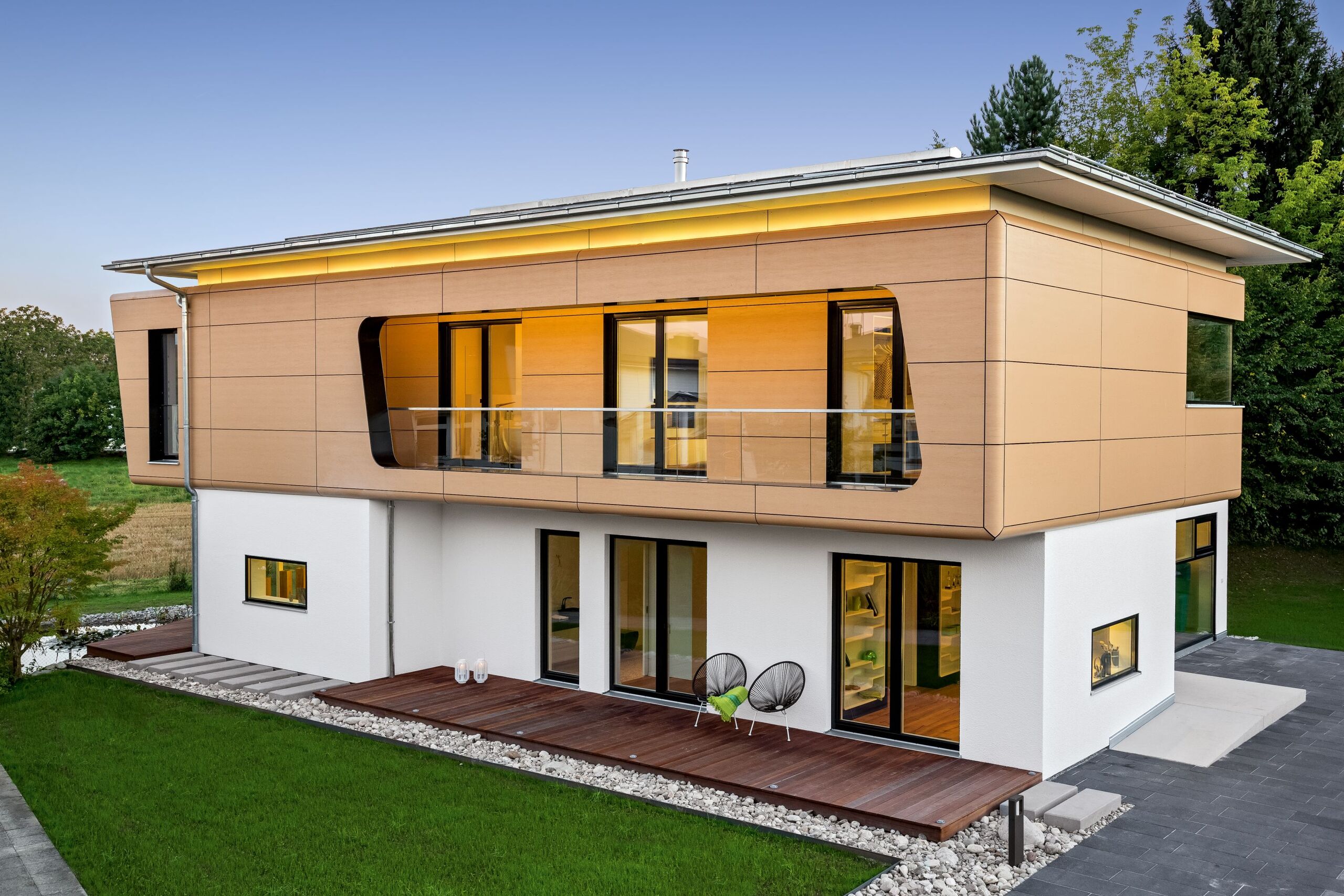 Eine elegante Villa mit barrierefreiem Hauseingang, seitlicher überdachter Terrasse, überdachter Loggia mit Glasgeländer, auskragendem Dachvorsprung und Fassadenelementen in Holzoptik von Regnauer.