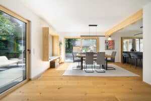 Eine offene Wohnküche in dem Regnauer Fertighaus "Andechs" mit Essbereich, Theke, zwei Holz-Alu-Terrassenschiebetüren und einem hellen Sitzfenster von Regnauer Hausbau.