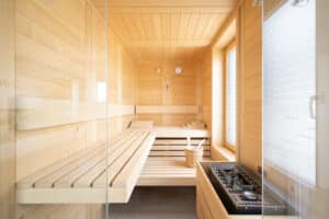 Ein Sauna‑ und Wellnessraum mit Holzliegen und zwei grossen Fenstern mit satiniertem Glas, der Licht und Privatsphäre harmonisch verbindet von Regnauer Hausbau.