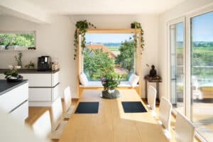 Ein offener Wohn‑ und Essbereich mit grossem Sitzfenster und Terrassentür für eine lichdurchflutet Wohnküche von Regnauer Hausbau.