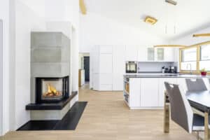 Ein moderner offener Wohnbereich mit Küche, Essplatz, Kamin, Dachschräge und großen Fensterflächen von Regnauer.