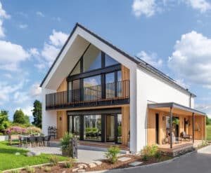 Modernes Einfamilienhaus "Klara" mit Satteldach, Balkon, Holzfassadenelementen und großzügiger überdachter Terrasse und überdachtem Eingangsbereich von Regnauer.