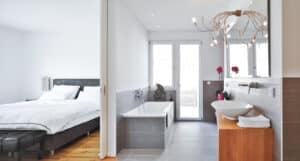Ein modernes Schlafzimmer mit Schiebetüre zum angrenzenden Badezimmer von Regnauer.