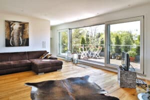 Wohnzimmer eines modernen Einfamilienhauses mit großzügigem Balkon und großflächigen Balkonschiebetüren von Regnauer.