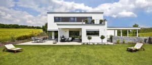 Ein modernes Flachdachhaus mit überdachtem Eingangsbereich, Terrasse, Dachterrasse, Balkon, Garten und Carport von Regnauer.