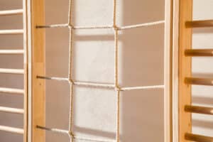 RÖFIX zeigt die Innenwand einer Turnhalle mit Sprossenwand und Kletterseilen in einem Kindergarten.