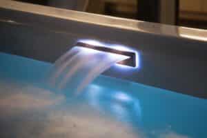 Ruha Stelzmüller zeigt eine Wasserfalldüse in einem Whirlpool mit beleuchteter Umrandung.